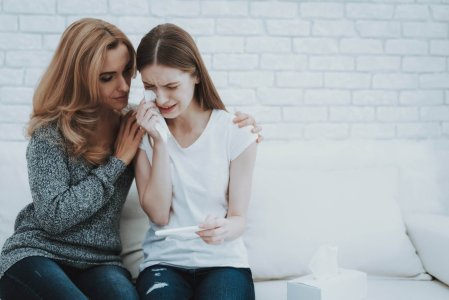 Mother near Upset Daughter with Pregnancy Test.